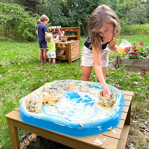 Children exploring a sensory tray outside